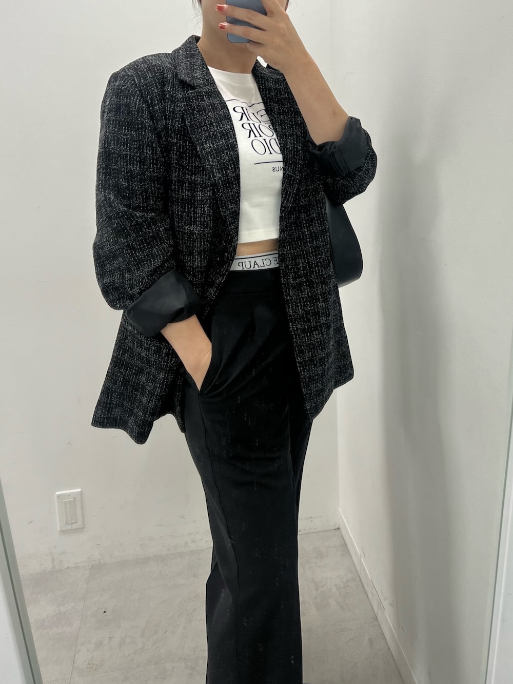 ブラック系のスラックス、ブラック系のローファー、ホワイト系のショルダーバッグを着用したレディースの夏コーディネートの2枚目の写真