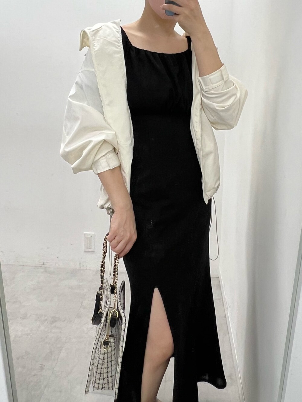 ブラック系のワンピース、ホワイト系のマウンテンパーカー、ホワイト系のサンダルを着用したレディースの春コーディネートの2枚目の写真