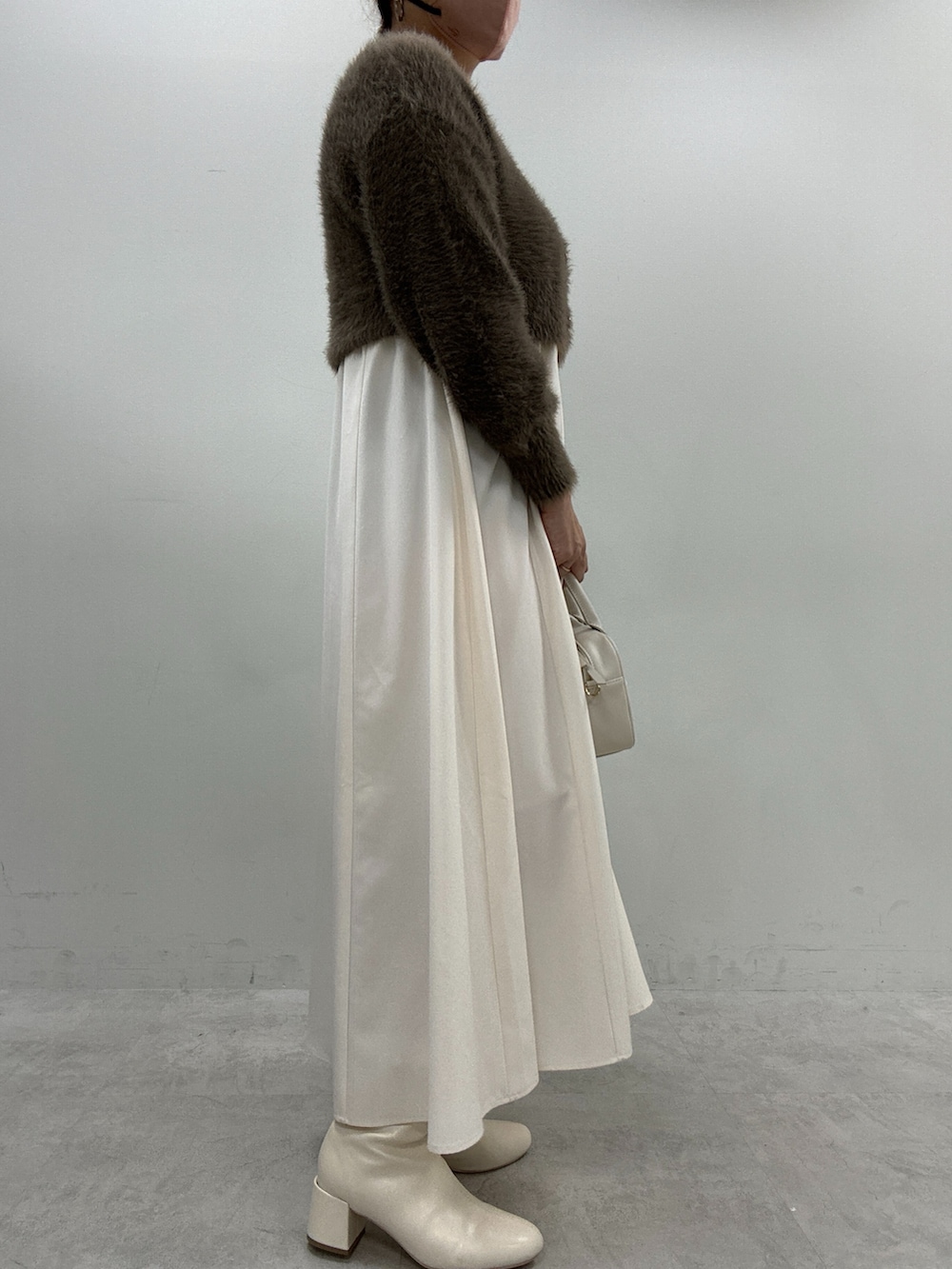 ベージュ系のワンピース、イエロー系のボストンバッグ、ブラウン系のカーディガン/ボレロを着用したレディースの秋コーディネートの2枚目の写真