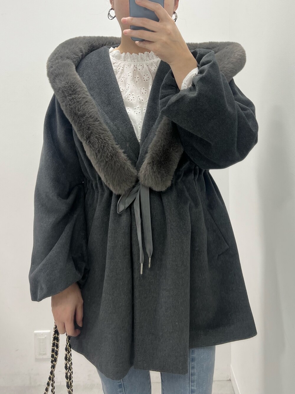 グレー系のポンチョ、ブルー系のデニムパンツ、ブラック系のバレエシューズを着用したレディースの冬コーディネートの2枚目の写真