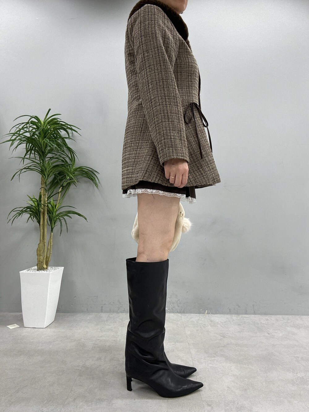 ブラウン系のノーカラーコート、ホワイト系のニット/セーター、ブラウン系のスカートを着用したレディースの秋コーディネートの3枚目の写真