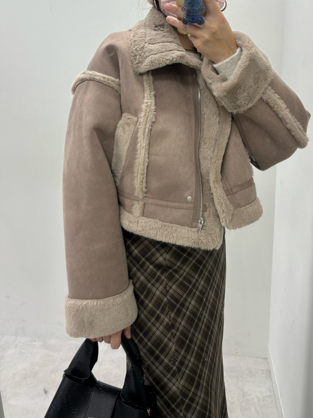 ブラウン系のスカート、ホワイト系のハンドバッグ、ブラウン系のムートンコートを着用したレディースの秋コーディネートの3枚目の写真