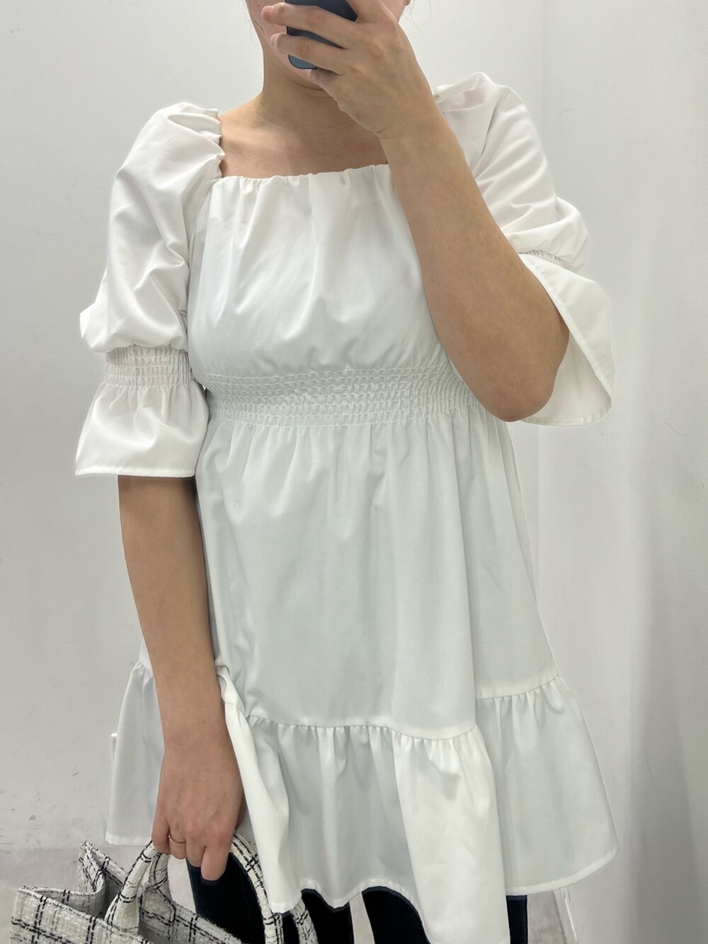 ホワイト系のチュニック、ブルー系のデニムパンツ、ホワイト系のトートバッグを着用したレディースの春コーディネートの2枚目の写真