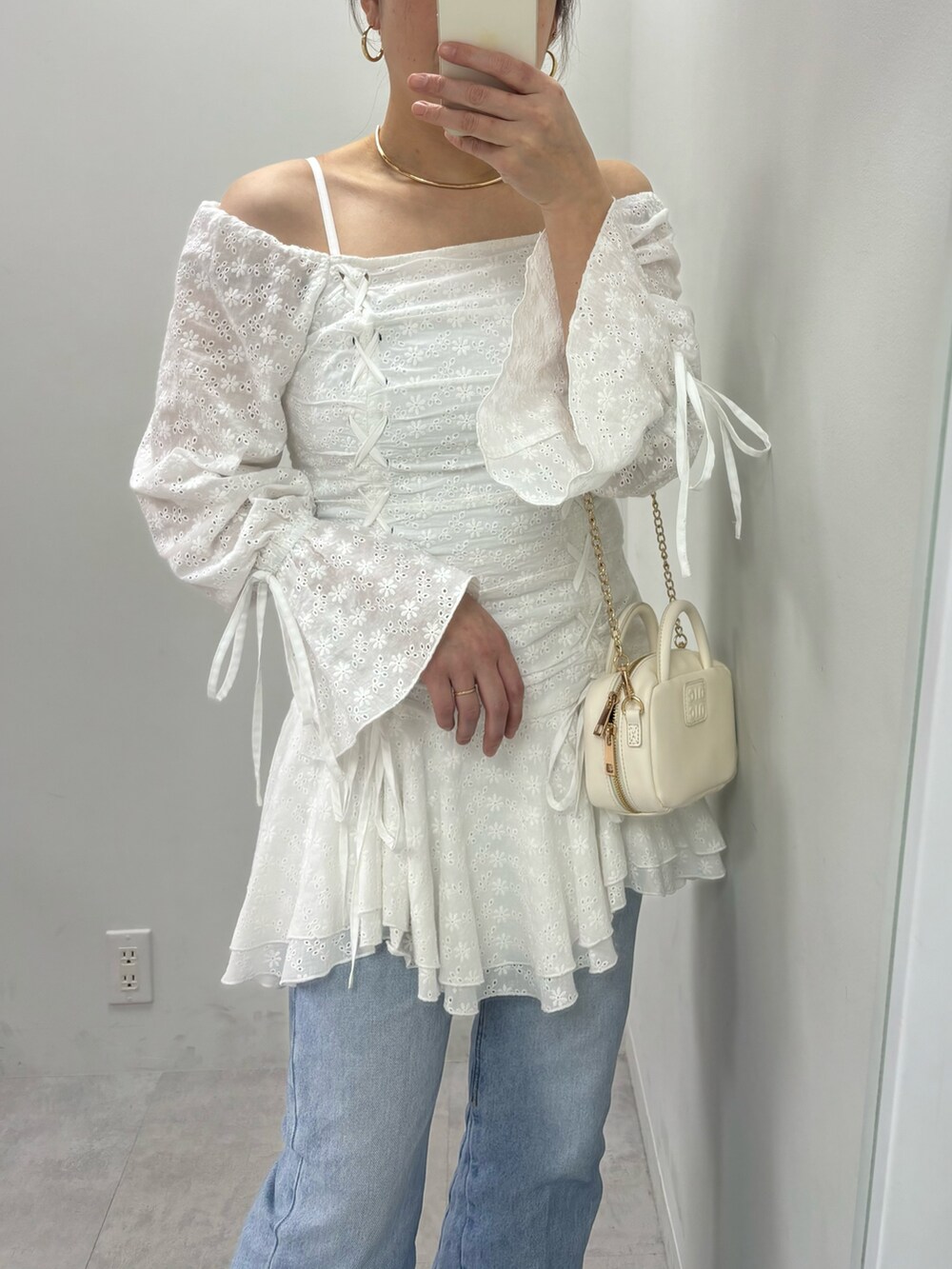 ブルー系のデニムパンツ、ホワイト系のボストンバッグ、ホワイト系のワンピースを着用したレディースの冬コーディネートの3枚目の写真