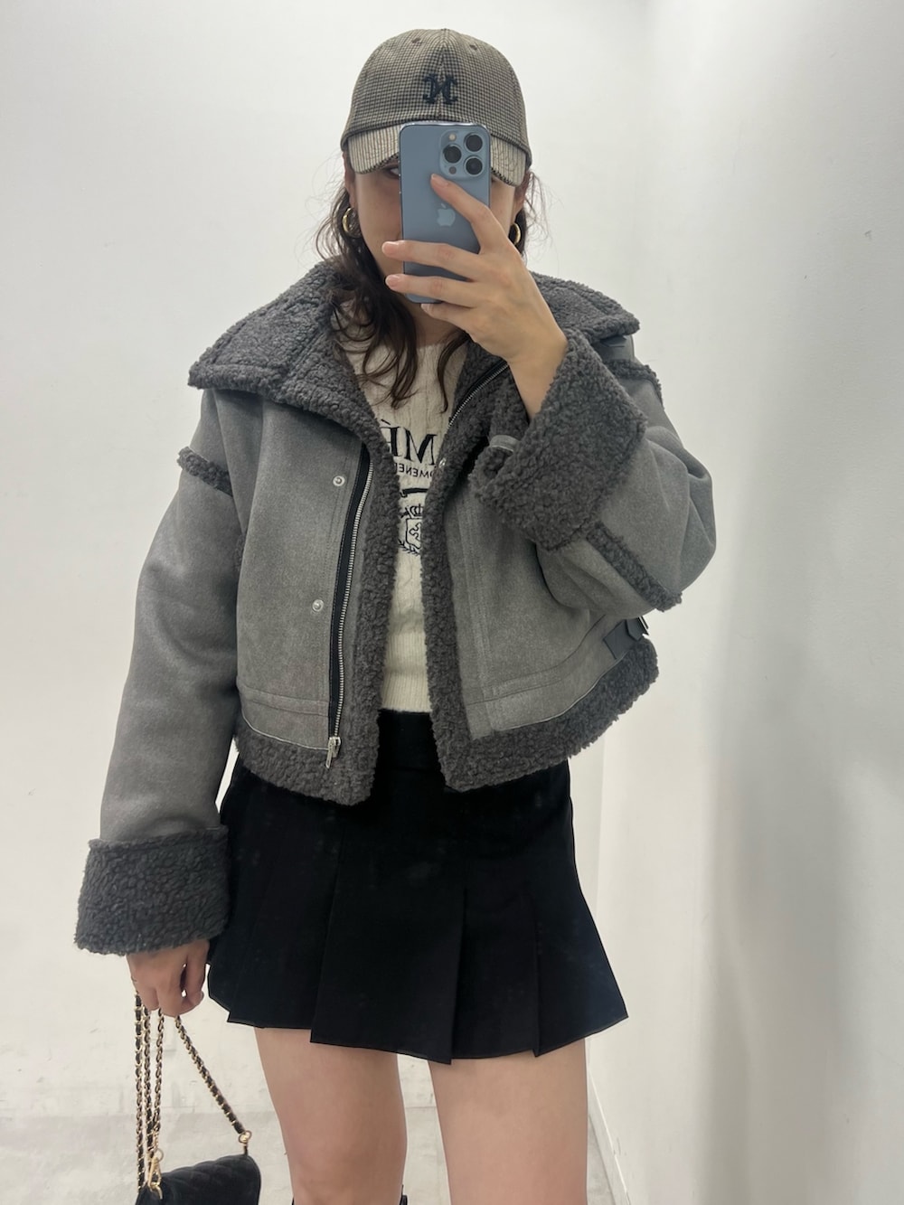 ブラック系のスカート、グレー系のムートンコート、ホワイト系のニット/セーターを着用したレディースの冬コーディネートの2枚目の写真