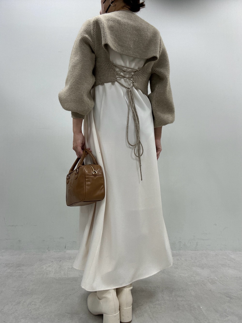 ブラック系のブーツ、ベージュ系のワンピース、イエロー系のボストンバッグを着用したレディースの秋コーディネートの3枚目の写真