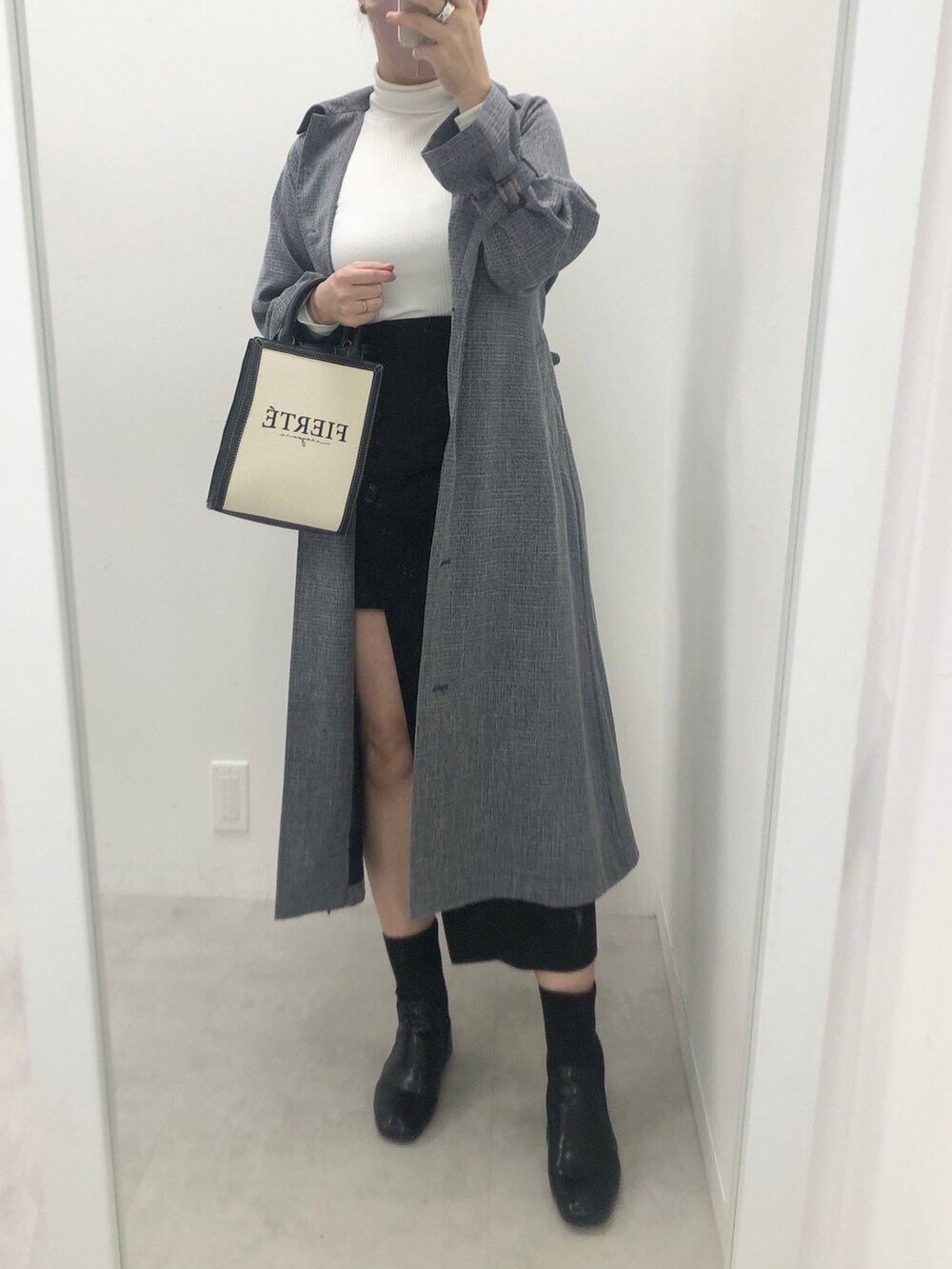 ブルー系のトレンチコート、ブラック系のスカート、ホワイト系のTシャツ/カットソーを着用したレディースの冬コーディネートの2枚目の写真