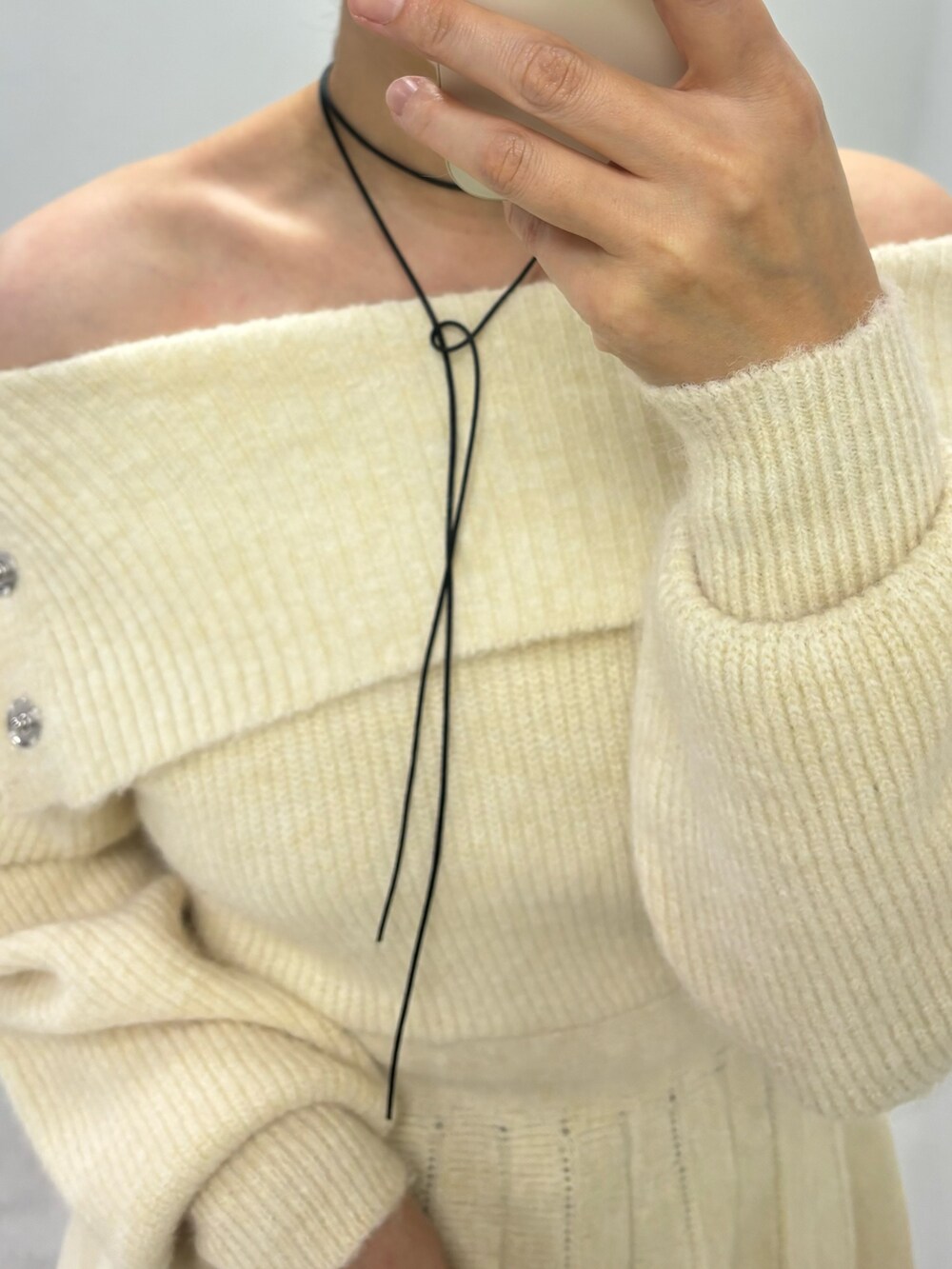 ホワイト系のワンピース、ブルー系のデニムパンツ、ブラック系のブーツを着用したレディースの秋コーディネートの5枚目の写真