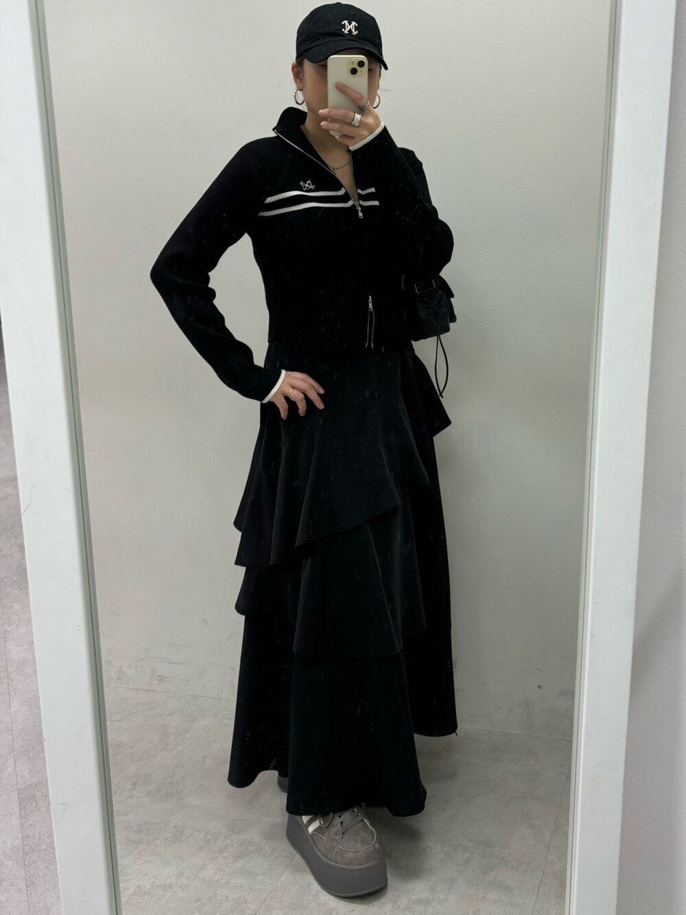 ブラック系のスカート、ブラック系のニット/セーター、グレー系のスニーカーを着用したレディースの秋コーディネートの3枚目の写真