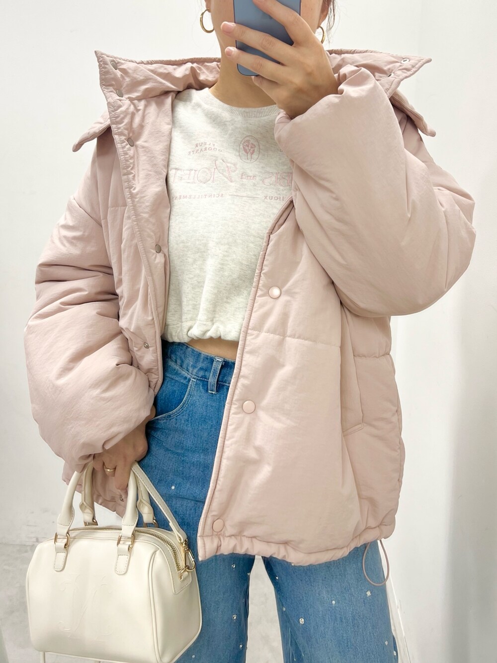 ホワイト系のハンドバッグ、ブルー系のデニムパンツ、ホワイト系のスニーカーを着用したレディースの秋コーディネートの2枚目の写真