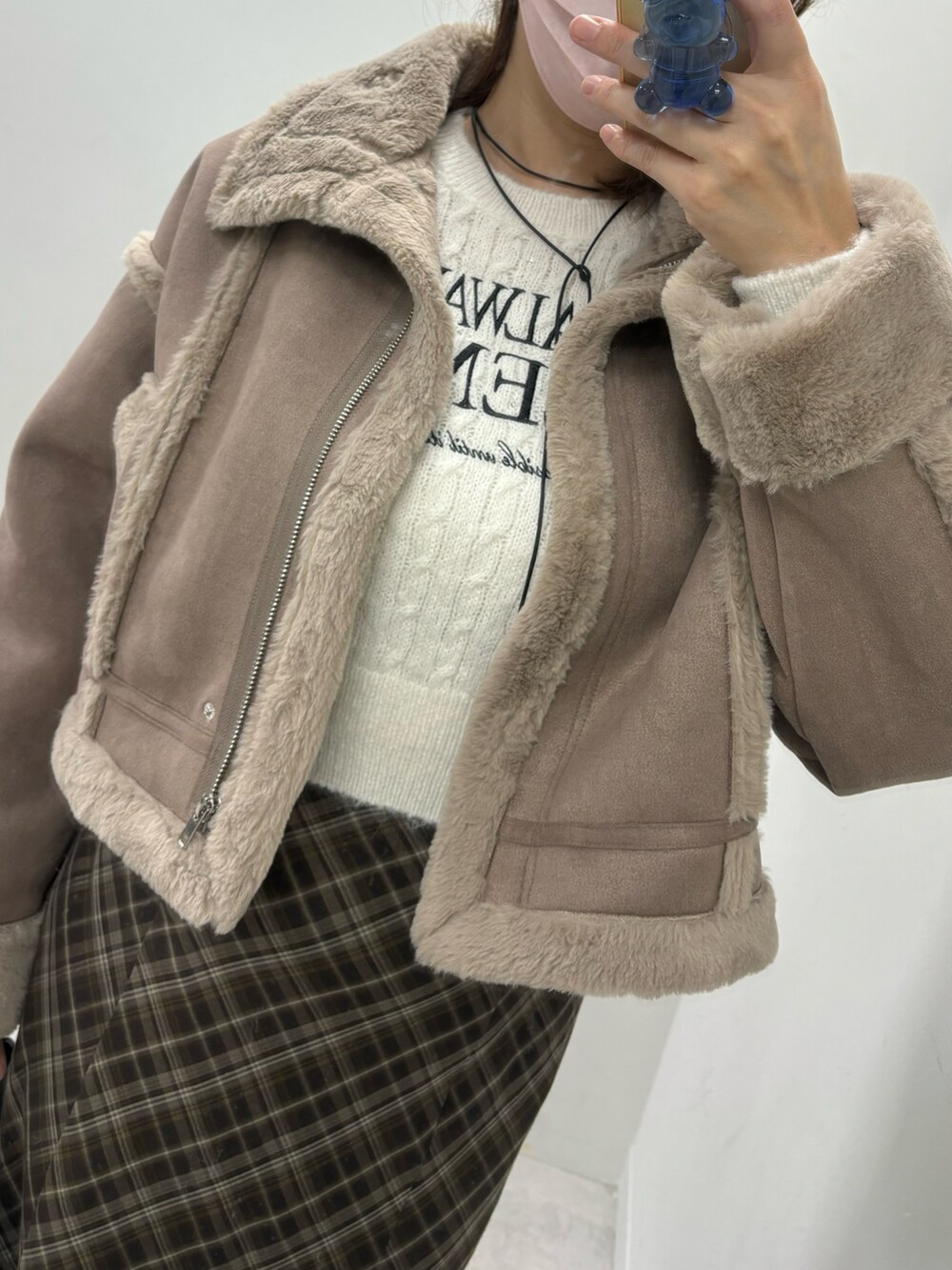 ブラウン系のスカート、ホワイト系のハンドバッグ、ブラウン系のムートンコートを着用したレディースの秋コーディネートの4枚目の写真