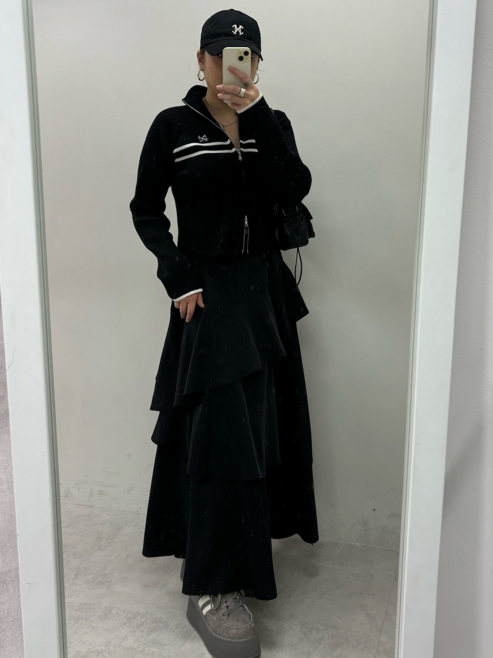 ブラック系のスカート、ブラック系のニット/セーター、グレー系のスニーカーを着用したレディースの秋コーディネートの2枚目の写真