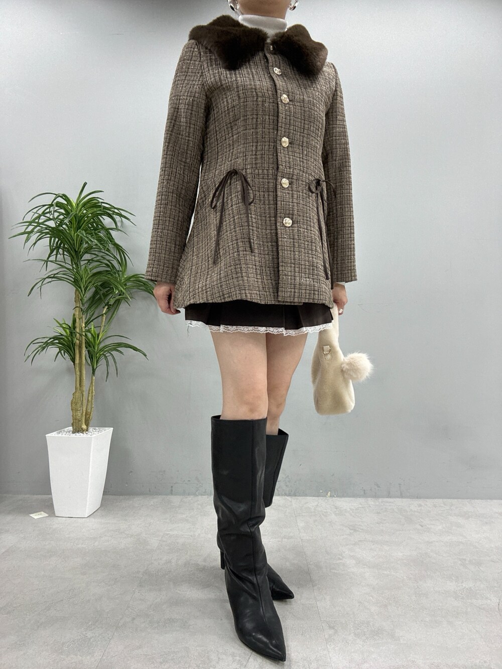 ブラウン系のノーカラーコート、ホワイト系のニット/セーター、ブラウン系のスカートを着用したレディースの秋コーディネートの2枚目の写真