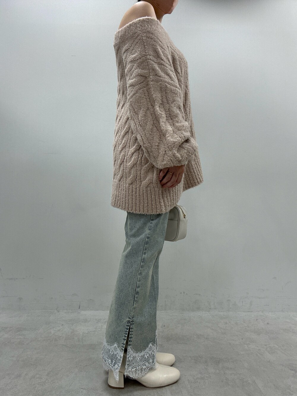 ブルー系のデニムパンツ、ベージュ系のニット/セーター、ブラック系のブーツを着用したレディースの秋コーディネートの2枚目の写真