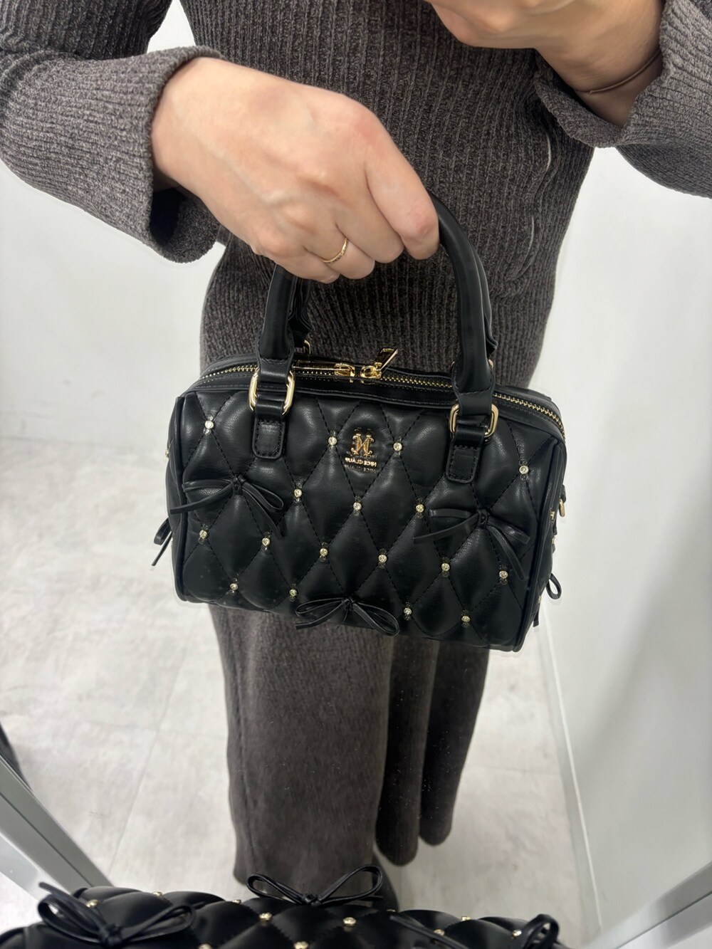 グレー系のワンピース、ブラック系のボストンバッグ、ブラック系のブーツを着用したレディースの秋コーディネートの6枚目の写真