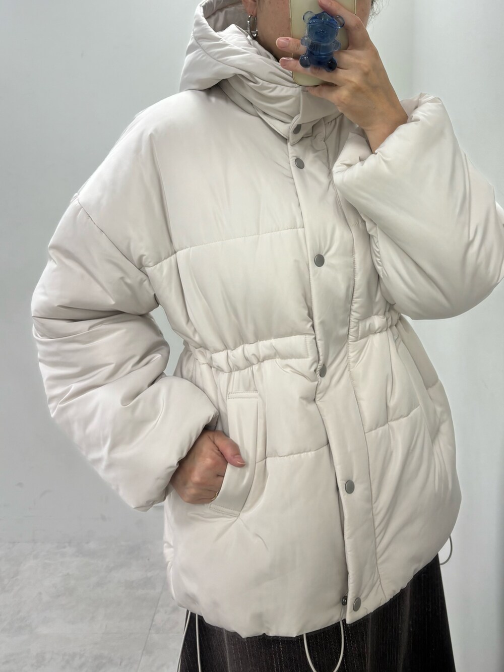 ブラウン系のスカート、ベージュ系のダウンジャケット/コート、ホワイト系のニット/セーターを着用したレディースの冬コーディネートの5枚目の写真