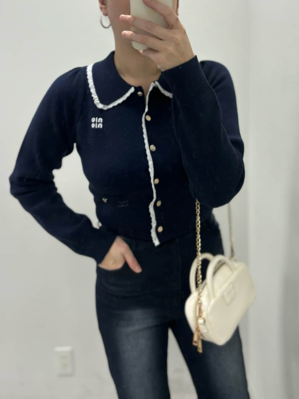 ブルー系のデニムパンツ、ホワイト系のボストンバッグ、ホワイト系のパンプスを着用したレディースの冬コーディネートの3枚目の写真
