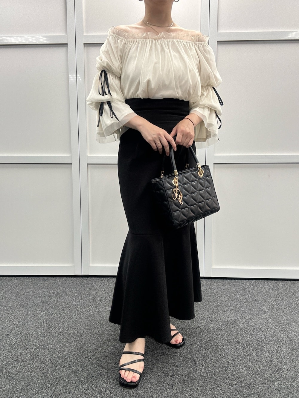 ブラック系のスカート、ブラック系のサンダル、ブラック系のトートバッグを着用したレディースの夏コーディネートの2枚目の写真