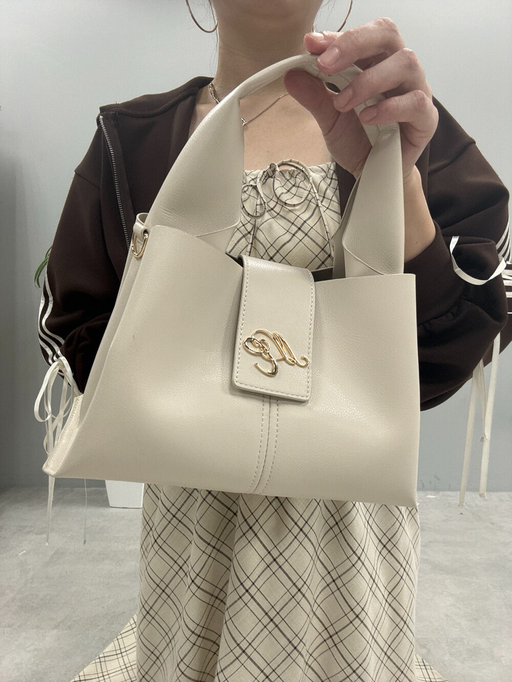 ブラウン系のパーカー、ブラック系のブーツ、ベージュ系のワンピースを着用したレディースの秋コーディネートの6枚目の写真