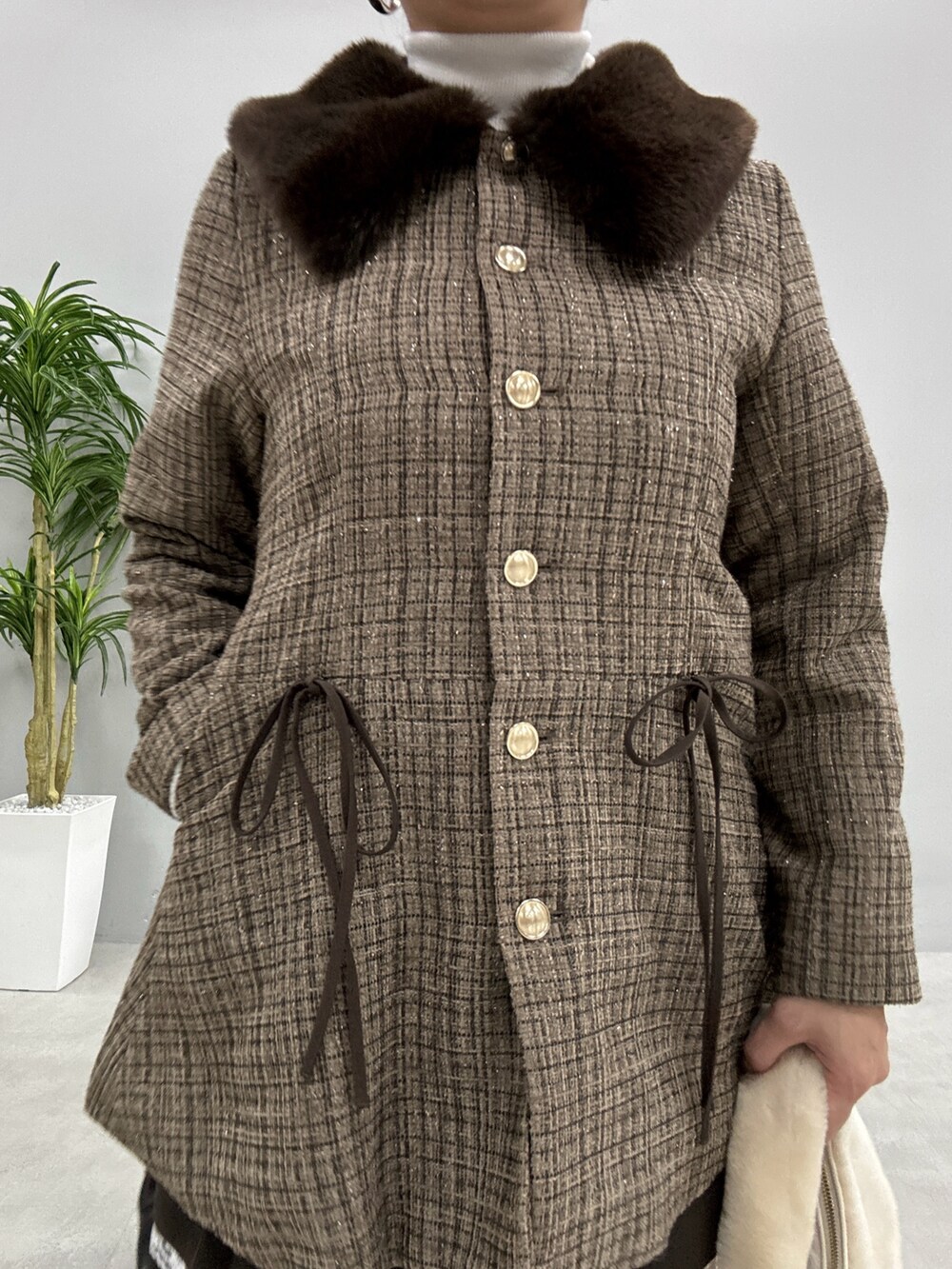 ブラウン系のノーカラーコート、ホワイト系のニット/セーター、ブラウン系のスカートを着用したレディースの秋コーディネートの4枚目の写真