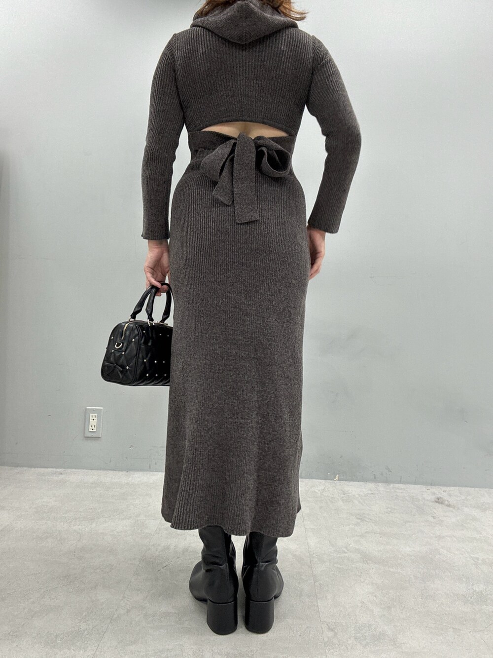 グレー系のワンピース、ブラック系のボストンバッグ、ブラック系のブーツを着用したレディースの秋コーディネートの3枚目の写真