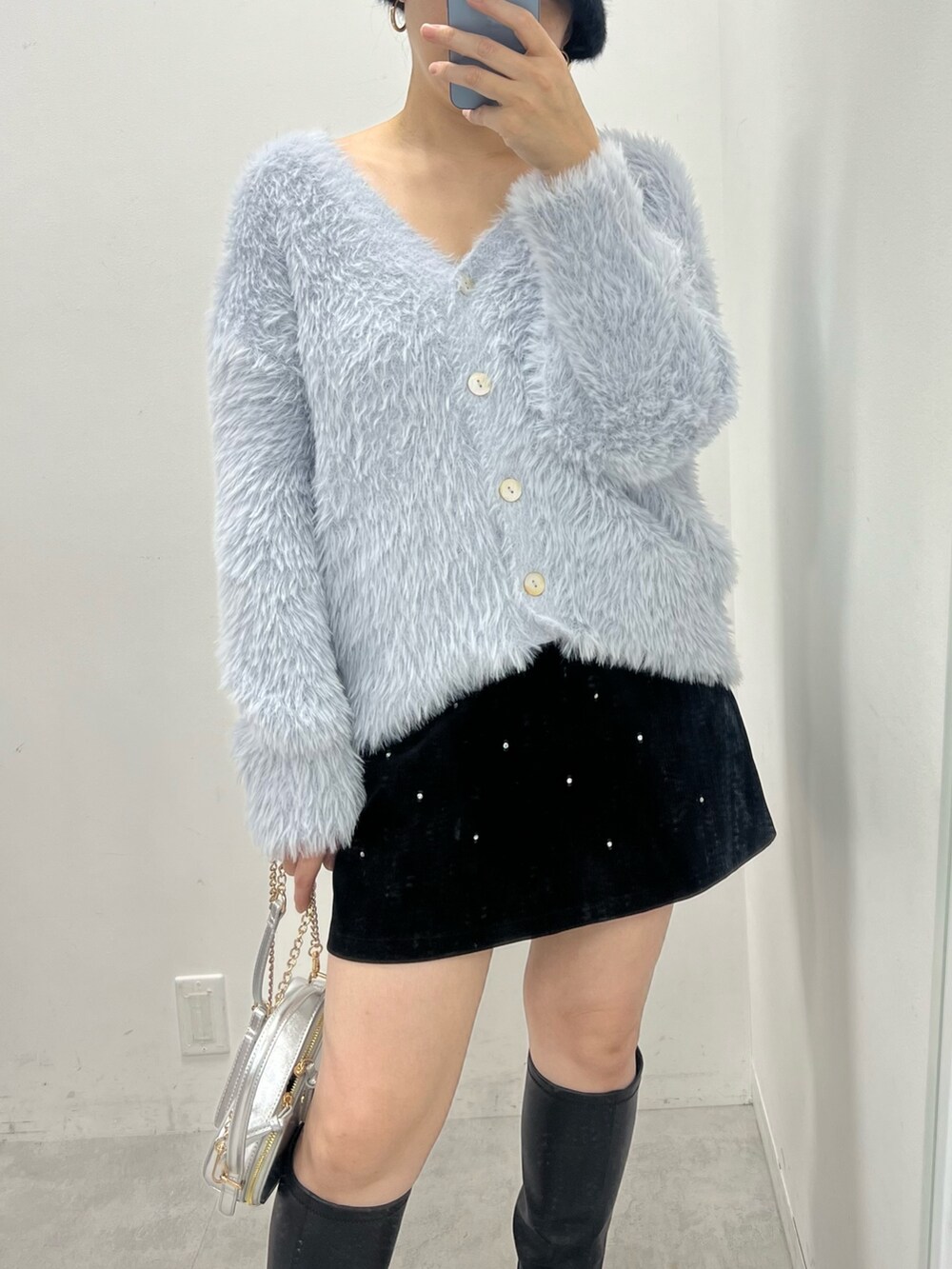 ブラック系のスカート、ホワイト系のカーディガン/ボレロ、シルバー系のショルダーバッグを着用したレディースの秋コーディネートの2枚目の写真