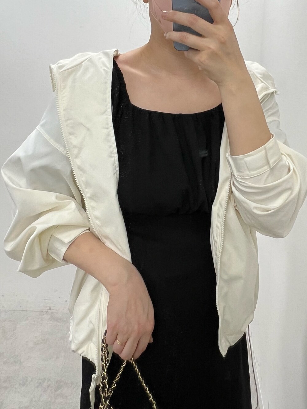 ブラック系のワンピース、ホワイト系のマウンテンパーカー、ホワイト系のサンダルを着用したレディースの春コーディネートの3枚目の写真