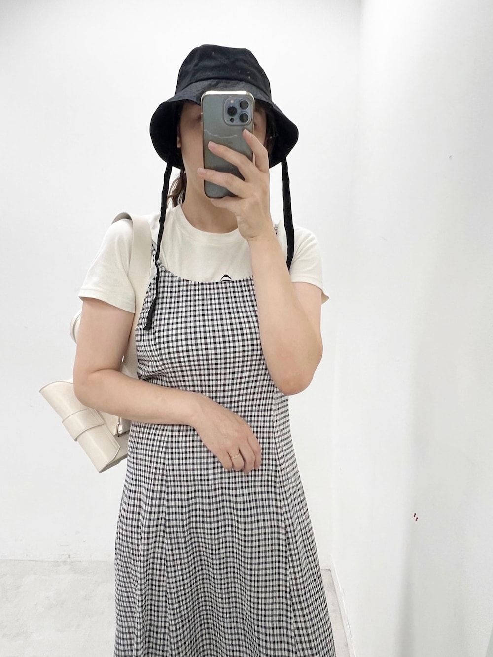 ブラック系のワンピース、ブラック系のブーツ、ホワイト系のショルダーバッグを着用したレディースの夏コーディネートの2枚目の写真