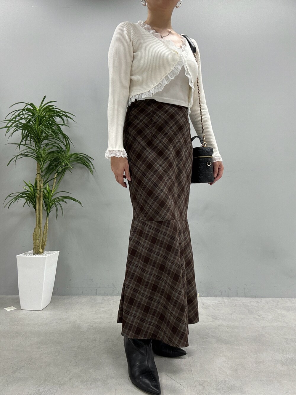 ブラウン系のスカート、ブラック系のショルダーバッグ、ホワイト系のカーディガン/ボレロを着用したレディースの秋コーディネートの2枚目の写真