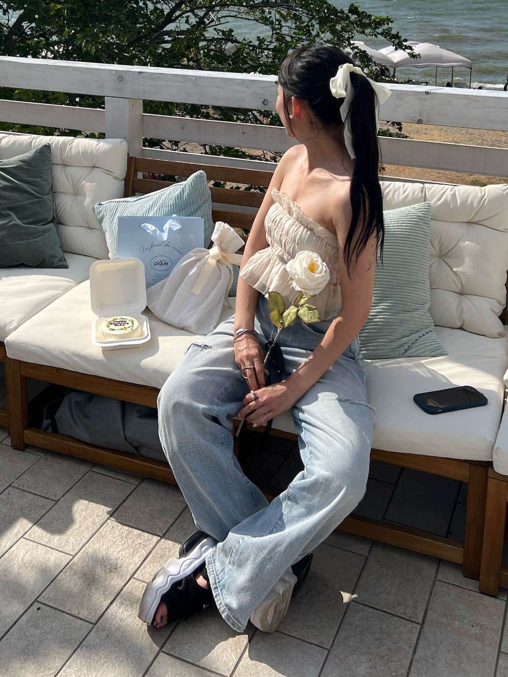 ブラック系のサンダル、ブルー系のデニムパンツ、ベージュ系のチューブトップを着用したレディースの夏コーディネートの2枚目の写真