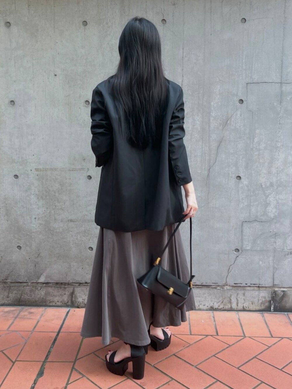ブラック系のテーラードジャケット、グレー系のワンピース、ブラック系のハンドバッグを着用したレディースの秋コーディネートの2枚目の写真