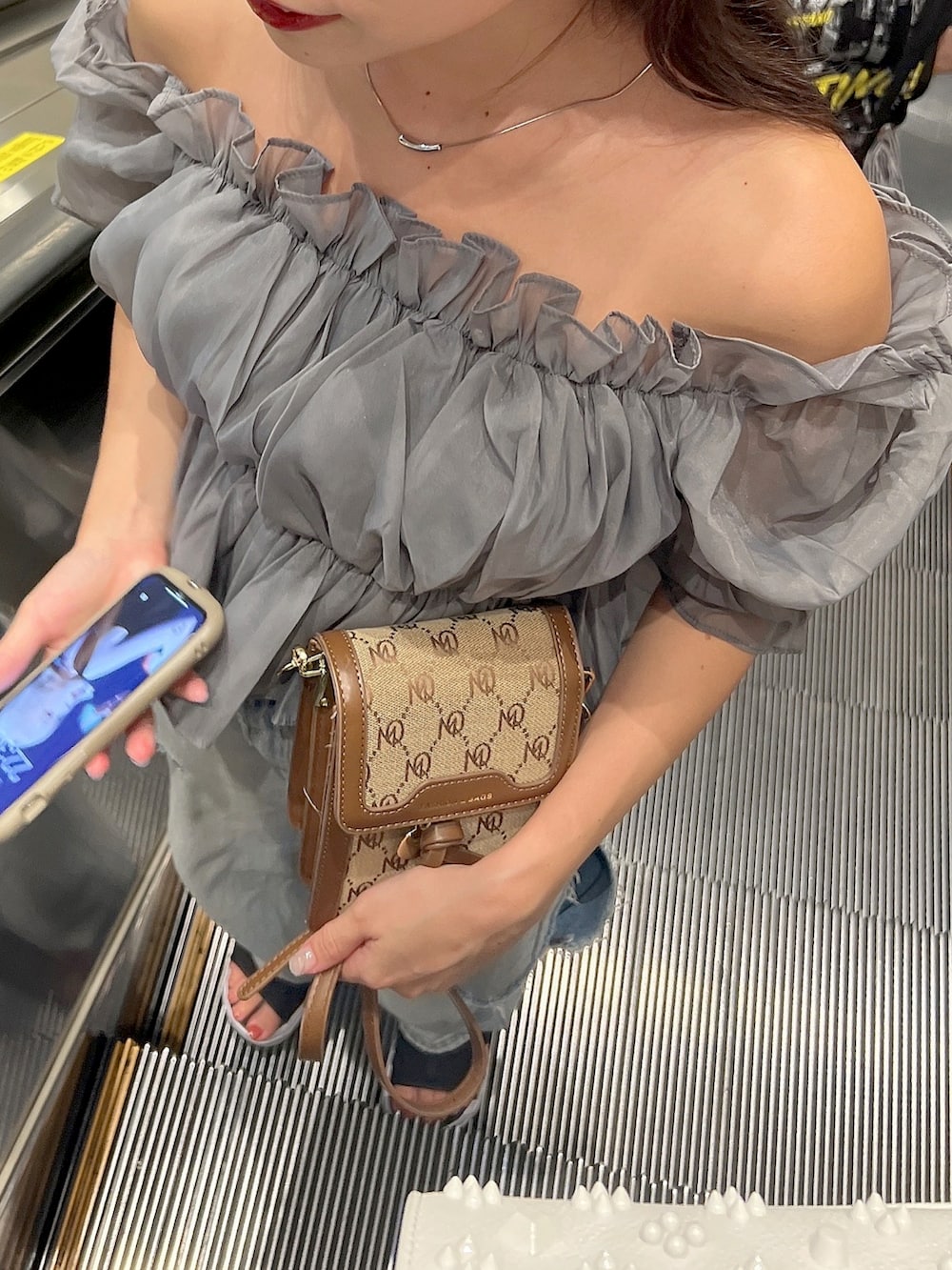 ブルー系のデニムパンツ、グレー系のシャツ/ブラウス、ブラウン系のショルダーバッグを着用したレディースの秋コーディネートの2枚目の写真