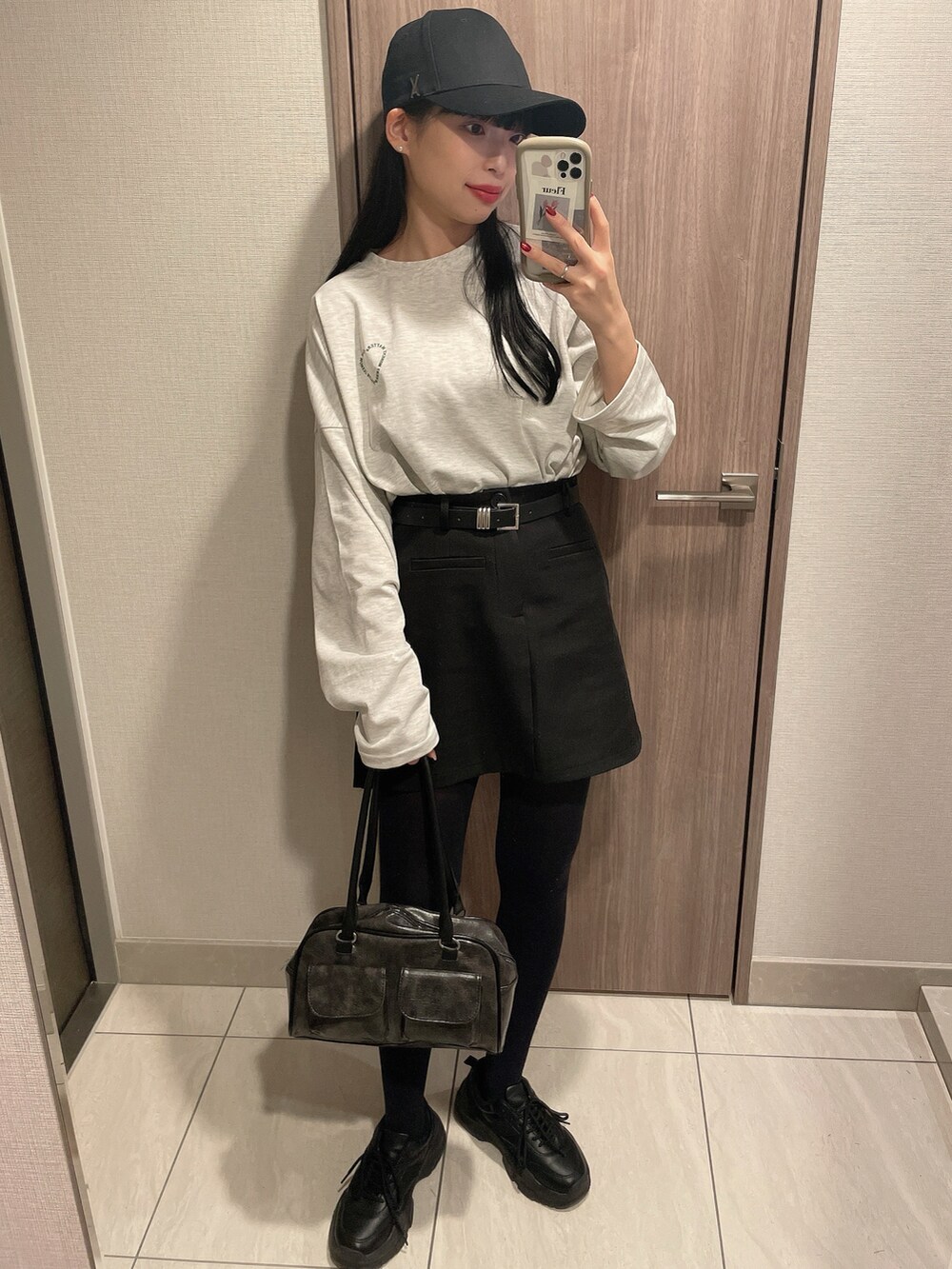 ブラック系のバッグ、ブラック系のスカート、ホワイト系のTシャツ/カットソーを着用したレディースの春コーディネートの2枚目の写真
