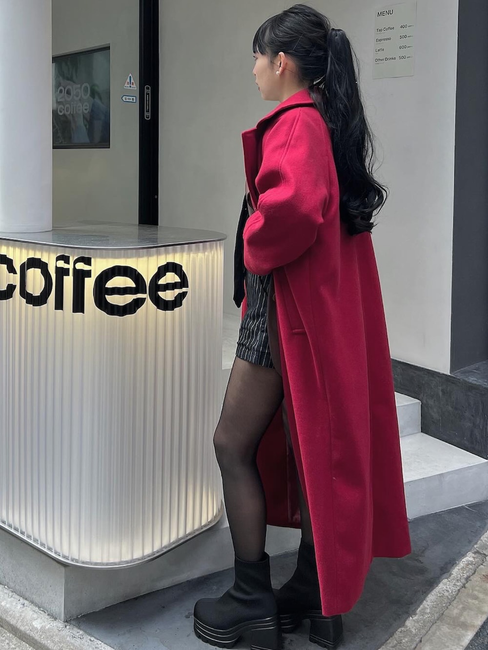 ブラウン系のボストンバッグ、ブラック系のブーツ、レッド系のチェスターコートを着用したレディースの春コーディネートの2枚目の写真