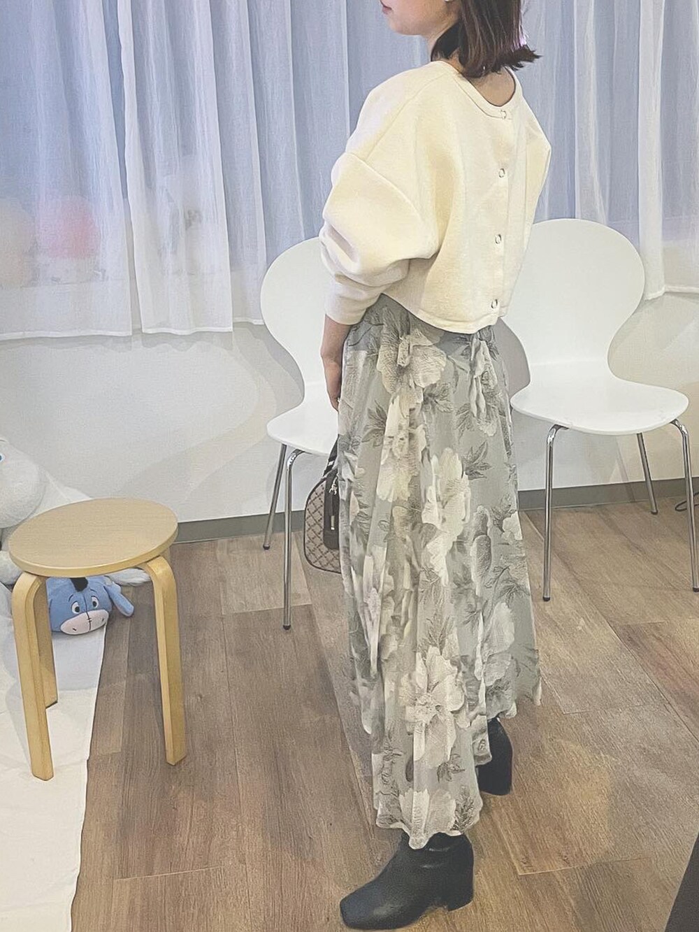 ホワイト系のカーディガン/ボレロ、グレー系のスカート、ブラウン系のボストンバッグを着用したレディースの冬コーディネートの2枚目の写真