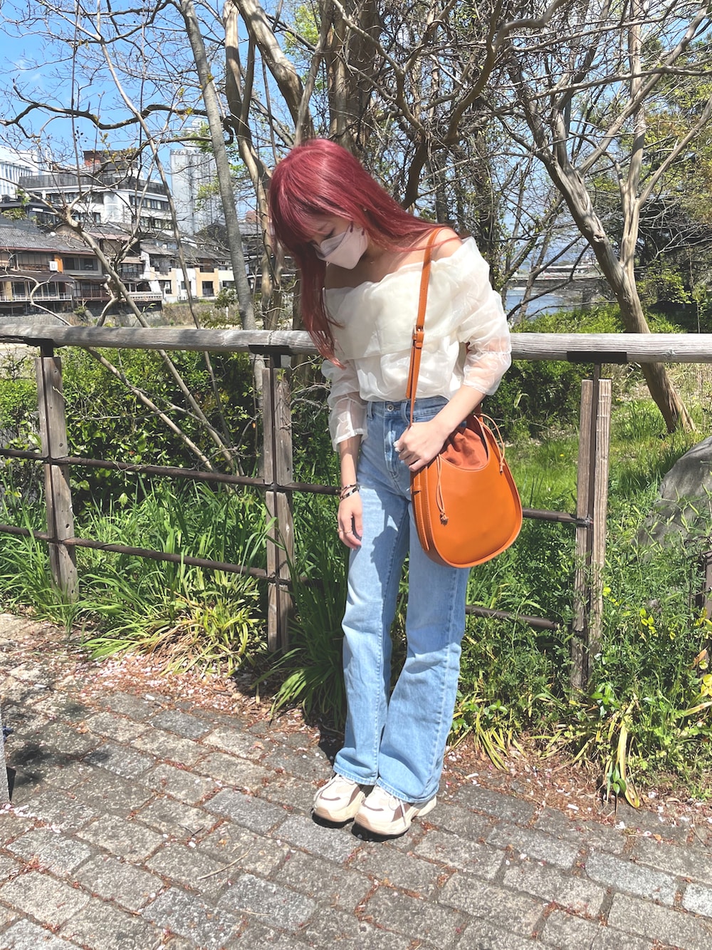 ベージュ系のシャツ/ブラウス、ブルー系のデニムパンツ、ブラウン系のショルダーバッグを着用したレディースの春コーディネートの2枚目の写真