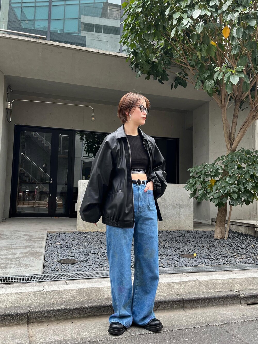 ブラック系のブルゾン、ブラック系のタンクトップ、ブルー系のデニムパンツを着用したレディースの冬コーディネートの3枚目の写真