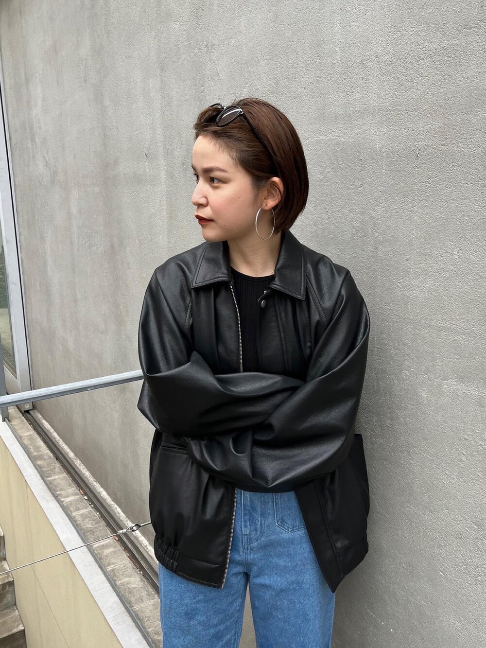 ブラック系のブルゾン、ブラック系のタンクトップ、ブルー系のデニムパンツを着用したレディースの冬コーディネートの2枚目の写真