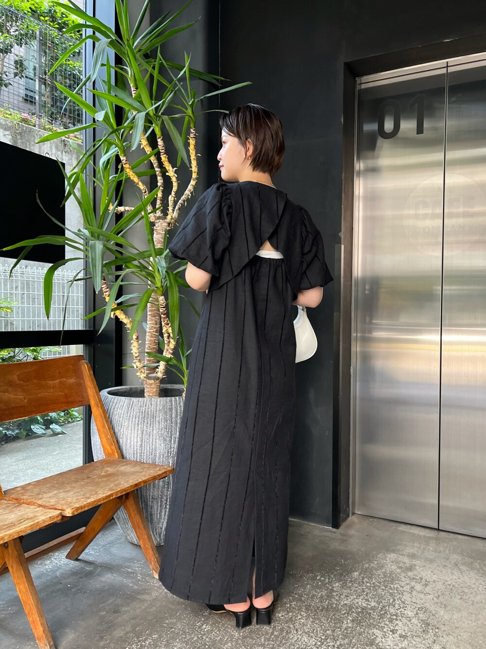 ブラック系のワンピース、ホワイト系のショルダーバッグを着用したレディースの春コーディネートの3枚目の写真