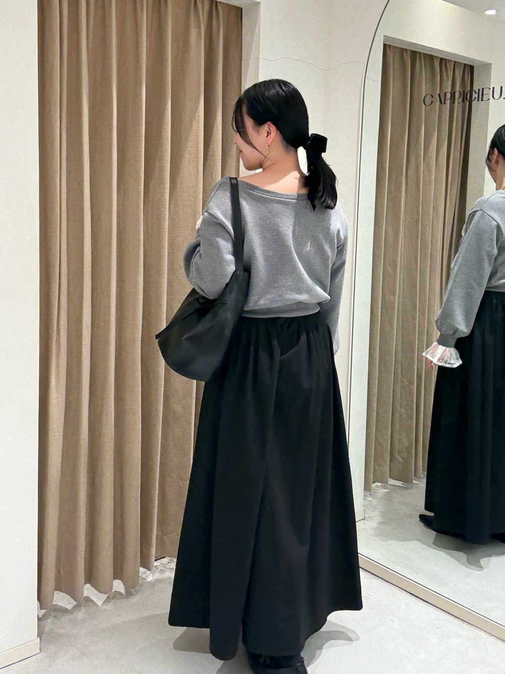 ブラック系のスカート、ブラック系のローファー、ブラック系のショルダーバッグを着用したレディースの春コーディネートの2枚目の写真