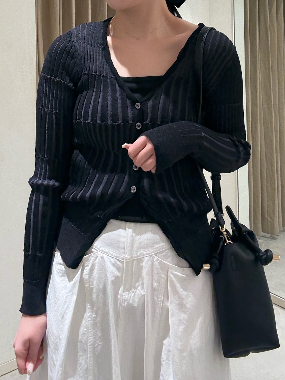 ホワイト系のスカート、ブラック系のカーディガン/ボレロ、ブラック系のショルダーバッグを着用したレディースの春コーディネートの3枚目の写真