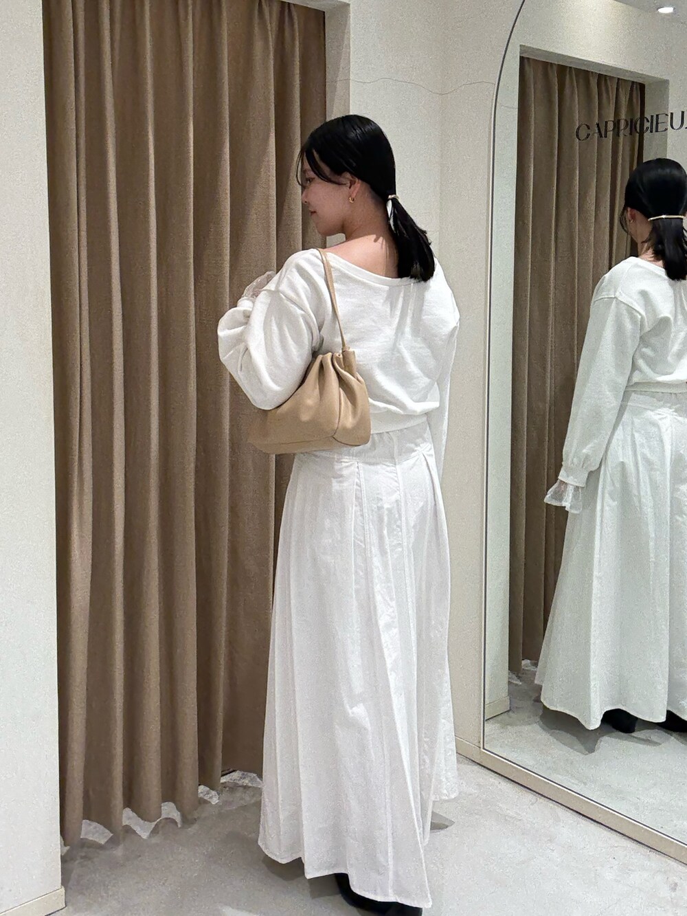 ホワイト系のスカート、ホワイト系のTシャツ/カットソー、ブラック系のパンプスを着用したレディースの春コーディネートの2枚目の写真