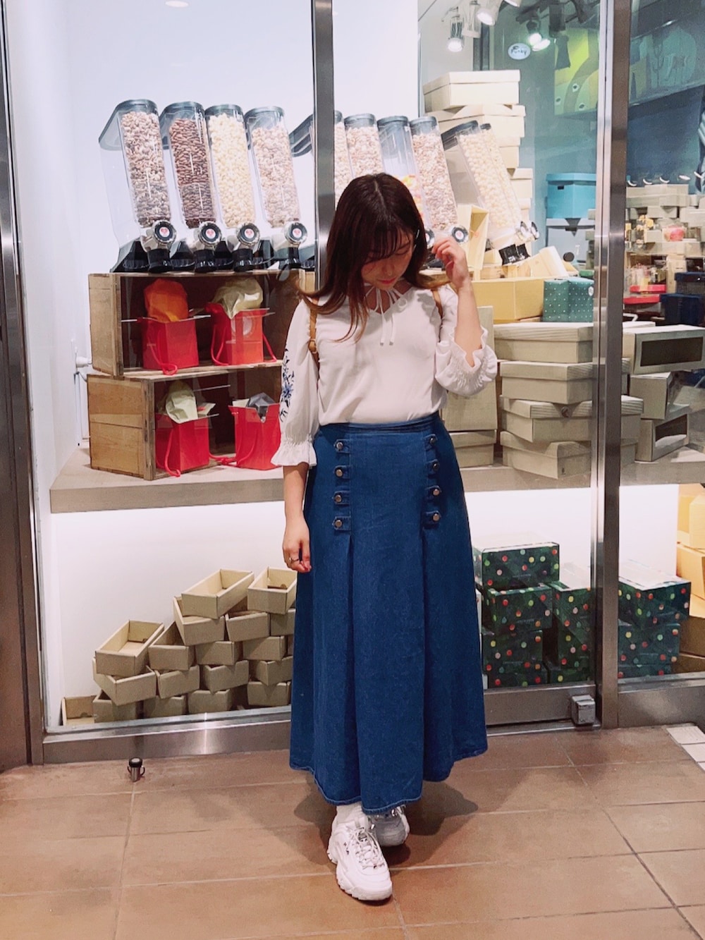 ブルー系のデニムスカート、ホワイト系のシャツ/ブラウス、ホワイト系のスニーカーを着用したレディースの春コーディネートの2枚目の写真