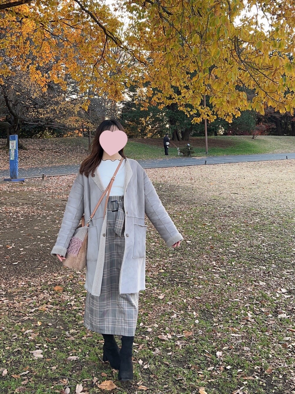 グレー系のスカート、ブラック系のブーツ、グレー系のムートンコートを着用したレディースの冬コーディネートの2枚目の写真