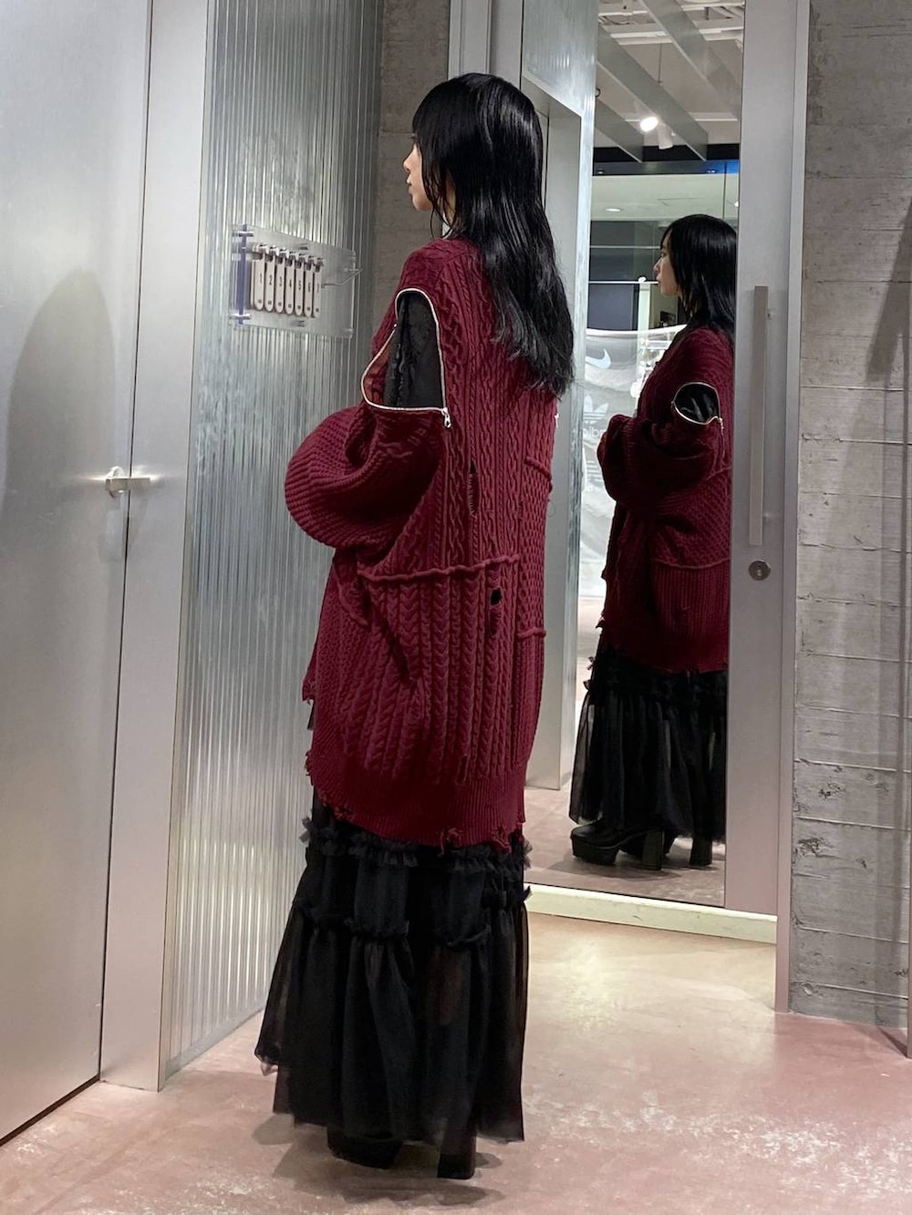 ブラック系のブーツ、レッド系のカーディガン/ボレロ、ブラック系のスカートを着用したレディースの秋コーディネートの2枚目の写真