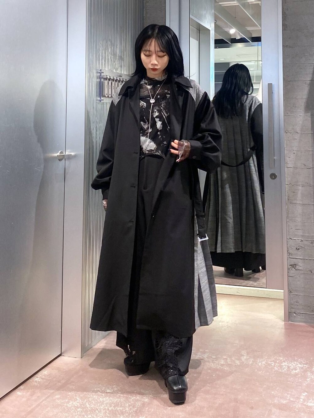 ブラック系のブーツ、ブラック系のステンカラーコート、ブラック系のTシャツ/カットソーを着用したレディースの秋コーディネートの6枚目の写真