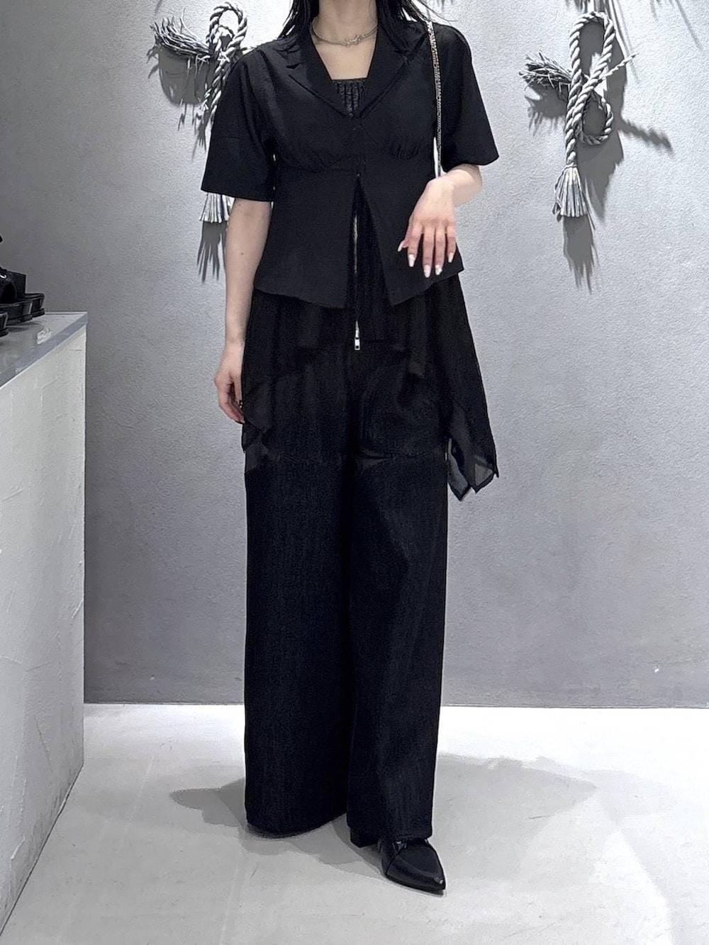 ブラック系のタンクトップ、ブラック系のサンダル、ブラック系のデニムパンツを着用したレディースの春コーディネートの5枚目の写真