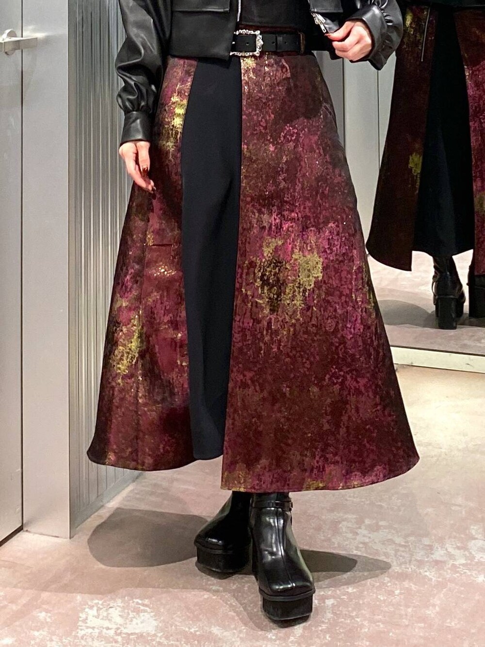 パープル系のスカート、ブラック系のブーツ、ブラック系のブルゾンを着用したレディースの秋コーディネートの7枚目の写真