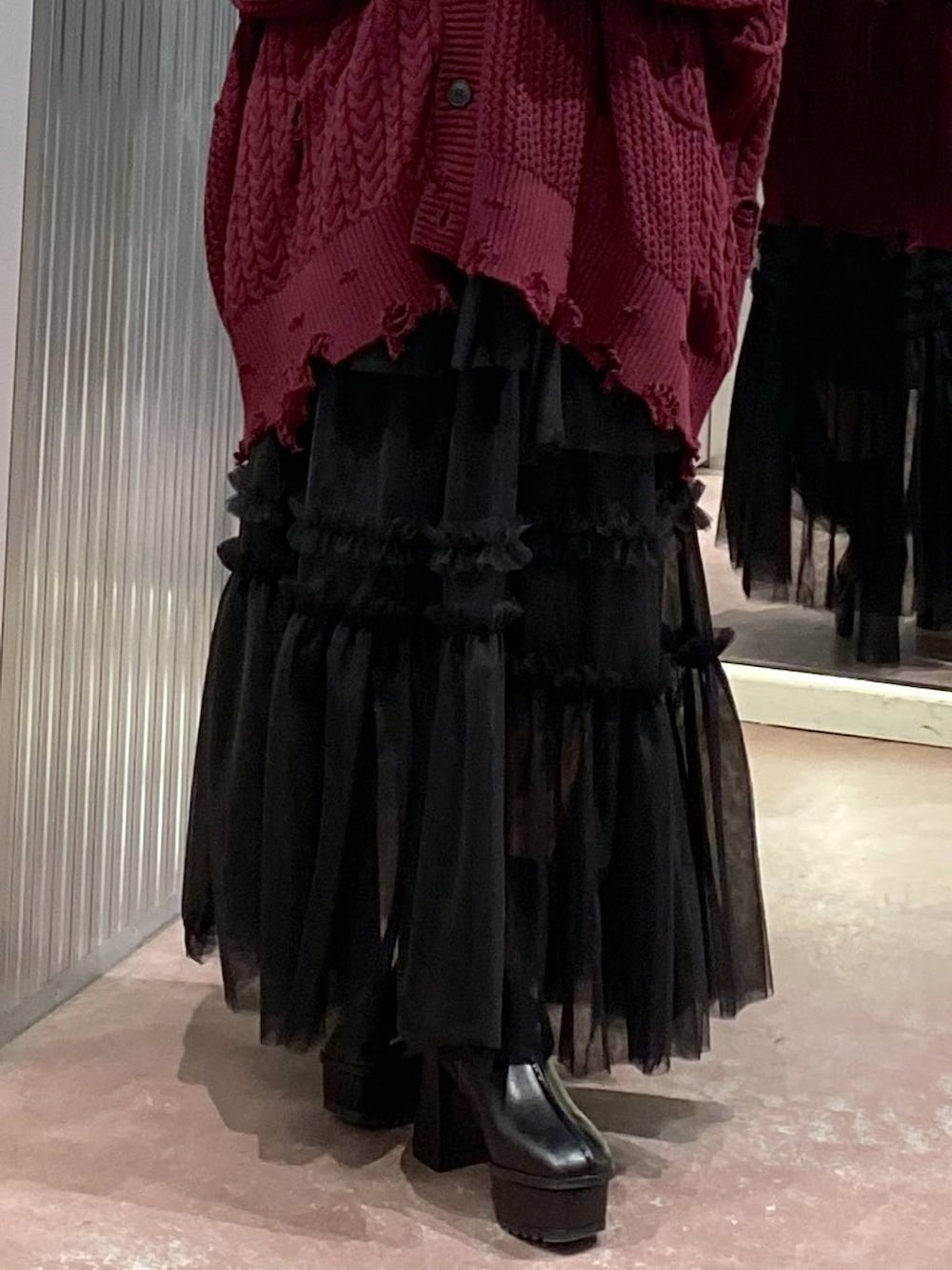 ブラック系のブーツ、レッド系のカーディガン/ボレロ、ブラック系のスカートを着用したレディースの秋コーディネートの8枚目の写真