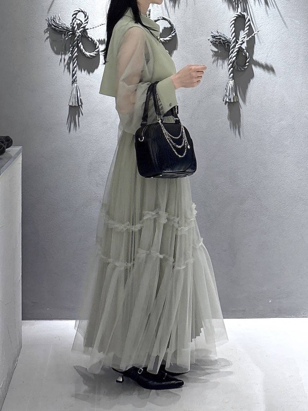 ブラック系のパンプス、ブラック系のショルダーバッグ、イエロー系のワンピースを着用したレディースの春コーディネートの3枚目の写真